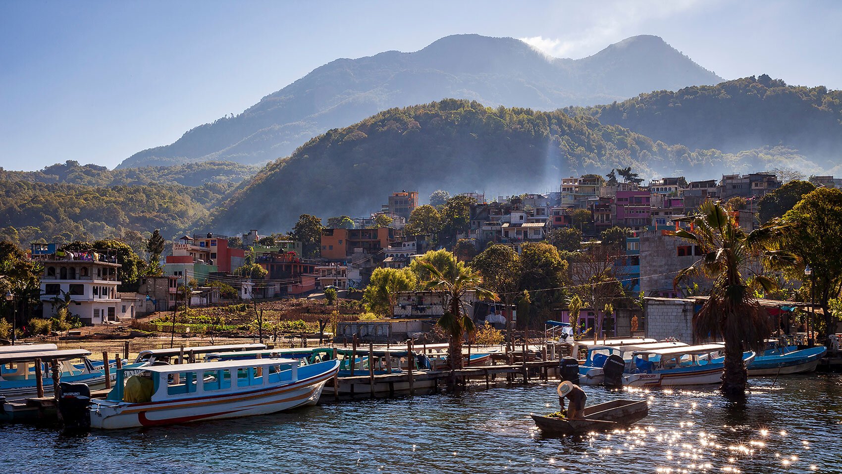 Moving to Guatemala a morning scene of a fisherman preparing in the morning with steaming volcano off in the distance on Lake Atitlan, Guatemala